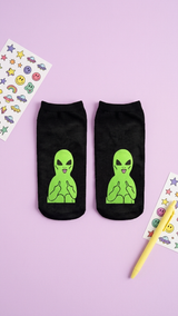 Pair of black ankle socks with neon green alien design making rude.